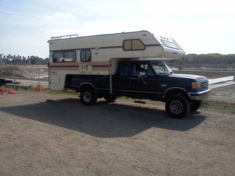 1991 Ford Bronco - This Ford F-350 truck is equipped with a camper shell, seen parked outdoors.