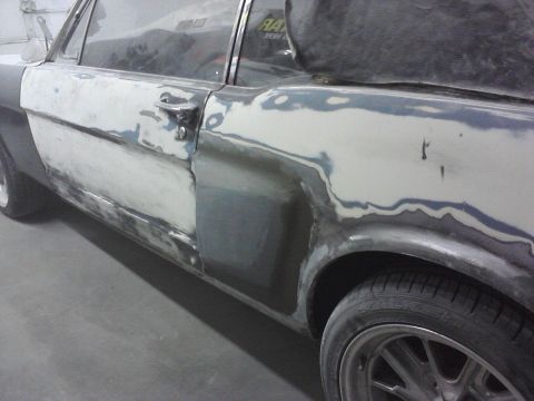 1966 Ford Mustang - Side view of a 1966 Ford Mustang undergoing body repair with filler applied.