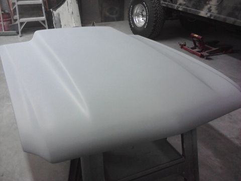 1966 Ford Mustang - A car hood, likely prepped for paint, is shown in a workshop setting with a Jeep in the background.