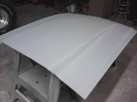 1966 Ford Mustang - A car hood, possibly undergoing bodywork, is displayed on sawhorses in a workshop setting.