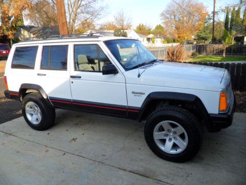 1994 Jeep Cherokee - White 1994 Jeep Cherokee Sport SUV with red pinstriping is shown from the front-three-quarter angle.