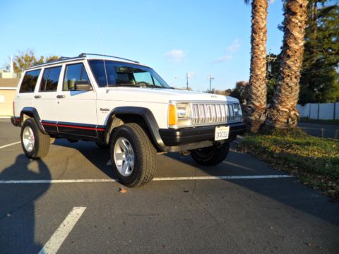 1994 Jeep Cherokee - A white 1994 Jeep Cherokee is parked in a lot under a clear blue sky.