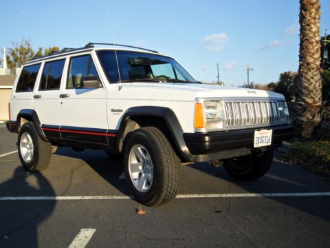 1994 Jeep Cherokee - A white 1994 Jeep Cherokee is parked in a lot under a clear sky.