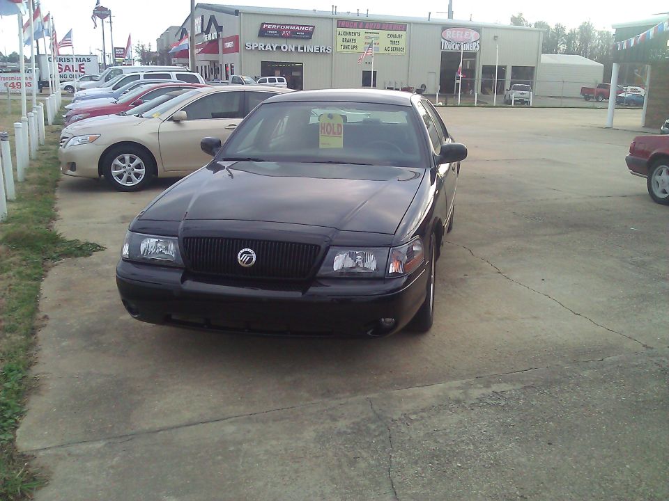 Black Mercury Grand Marquis sedan on used car lot with HOLD sign