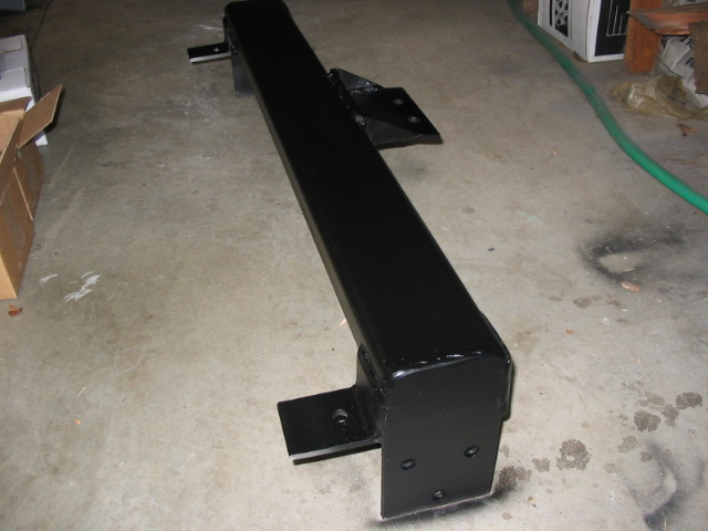 Freshly painted black square-tube custom bumper with welded brackets on a garage floor