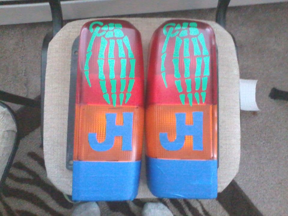 Pair of red and orange tail lights with green skeleton hand decals and blue 'JH' lettering