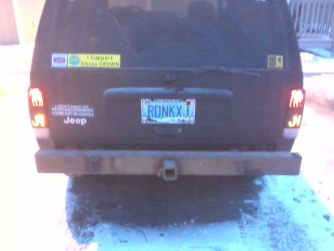 1998 Jeep Cherokee - Rear view of a black Jeep SUV with stickers on the tailgate and a trailer hitch.