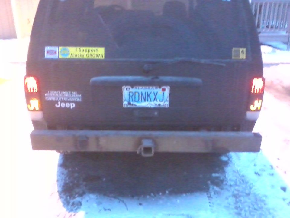 Black Jeep SUV rear view with a trailer hitch and Alaska license plate RDNKXJ