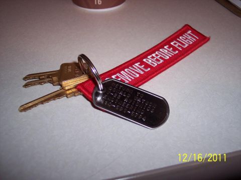 2000 Ford Crown Victoria - A set of keys with a 'Remove Before Flight' tag and a dog tag are resting on a table.