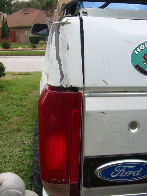 1992 Ford Bronco - This 1992 Ford Bronco shows significant paint damage on its rear quarter panel, with a visible Ford emblem below.