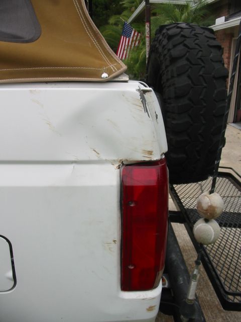 1992 Ford Bronco - Rear quarter panel damage on a white 1992 Ford Bronco with a spare tire mounted externally.
