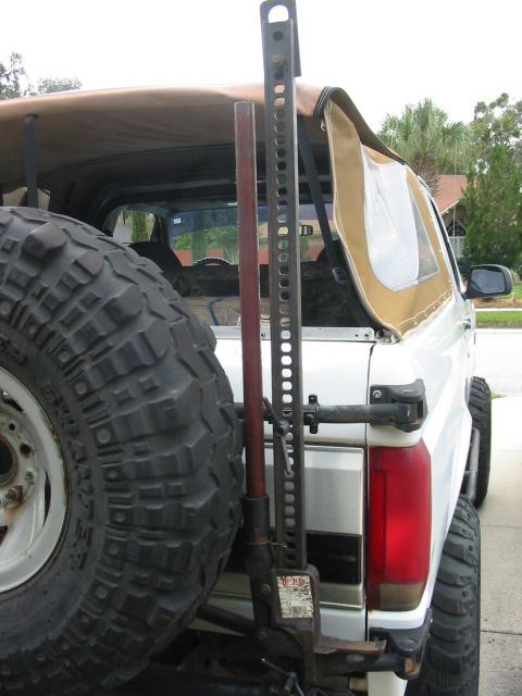 1992 Ford Bronco - The rear of a 1992 Ford Bronco is shown with a spare tire and a Hi-Lift jack attached to the tailgate.