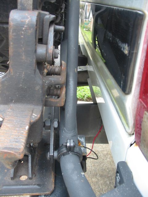 1992 Ford Bronco - Detail of a jack mechanism adjacent to the side of a white vehicle, with a red wire visible.