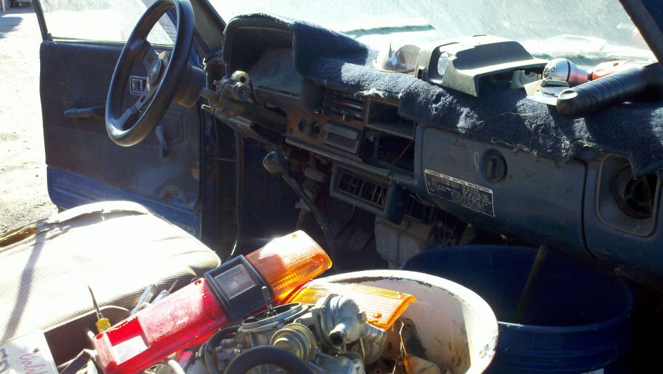 Stripped compact pickup interior with gutted dash, Toyota ID plate and tail lights piled on the seat