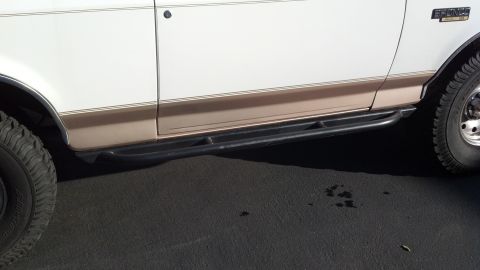 1996 Ford Bronco - Side view of a 1996 Ford Bronco aftermarket rock sliders and off-road tires.
