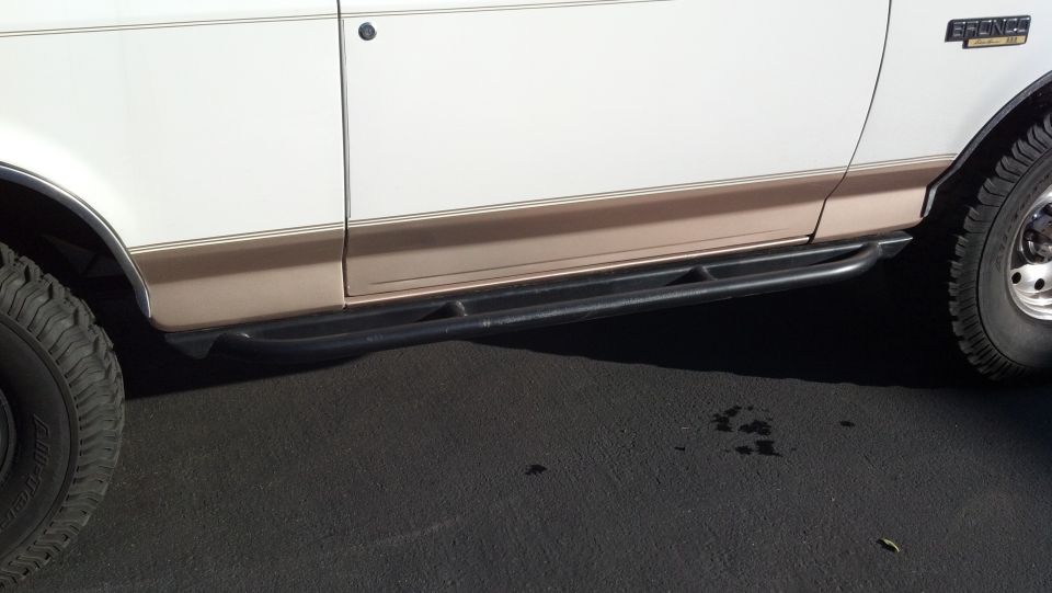 White and tan 1996 Ford Bronco side with rock sliders and off-road tires