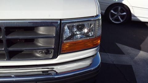 1996 Ford Bronco - Front view of a white truck's grille and headlight, with another vehicle in the background.