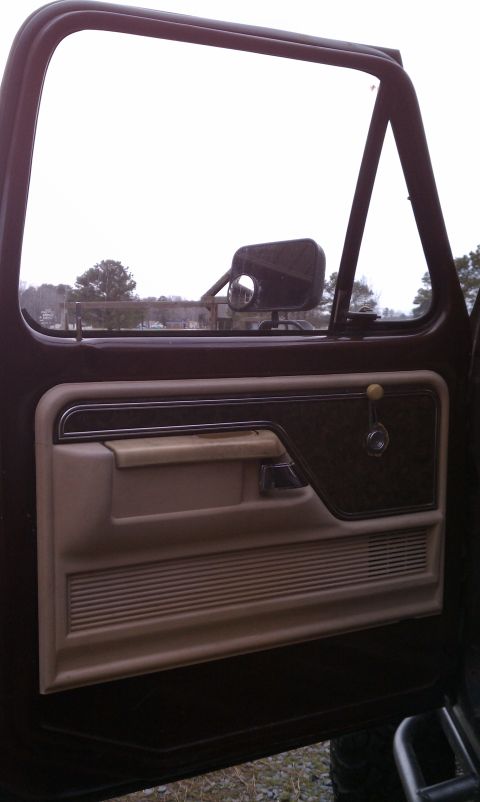 1979 Ford Bronco - Interior view of a 1979 Ford Bronco door panel, showing the tan and brown trim with chrome accents.