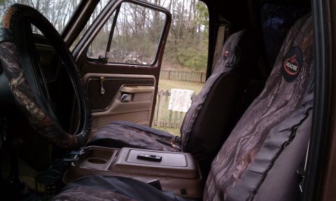 1979 Ford Bronco - The interior of a 1979 Ford Bronco features camouflage seat covers over brown upholstery and a brown dashboard.