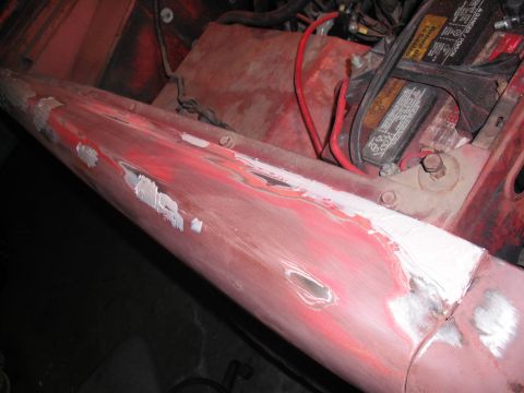 1968 Ford Bronco - Bodywork in progress on a red front fender top and inner apron, with dents sanded down to bare metal and skim coats of white body filler fe…