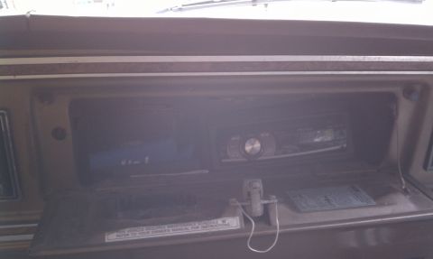 1979 Ford Bronco - The dashboard of a vehicle shows an aftermarket stereo system installed in the center console area.