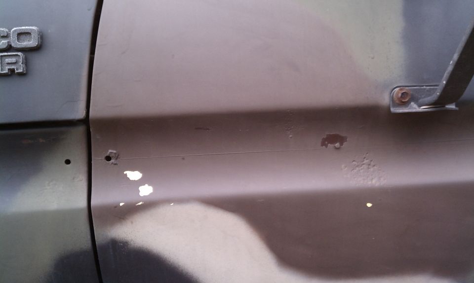 Close-up of a 1979 Ford Bronco door panel with 'BRONCO' badge visible