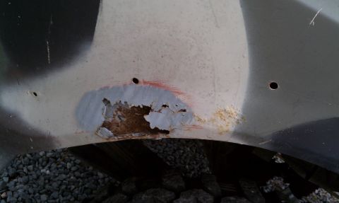 1979 Ford Bronco - Close-up of a heavily rusted vehicle fender with camouflage paint, indicating significant wear and tear.