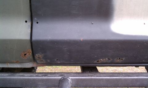 1979 Ford Bronco - Close-up of a vehicle's side panel reveals extensive rust and damage, with a Supermotors watermark at the bottom.