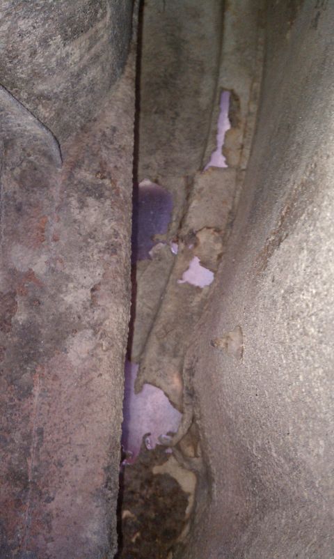 1979 Ford Bronco - Detail of a vehicle's undercarriage showing rust and remnants of purple paint.