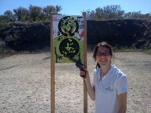 1996 Ford Bronco - A woman smiles while holding a revolver at a shooting range with a target behind her.