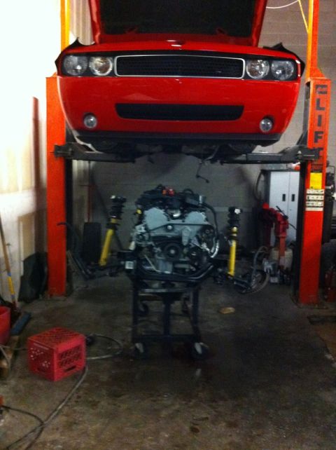 2010 Dodge Challenger - A red Dodge Challenger is on a car lift with its engine removed and placed on a stand.