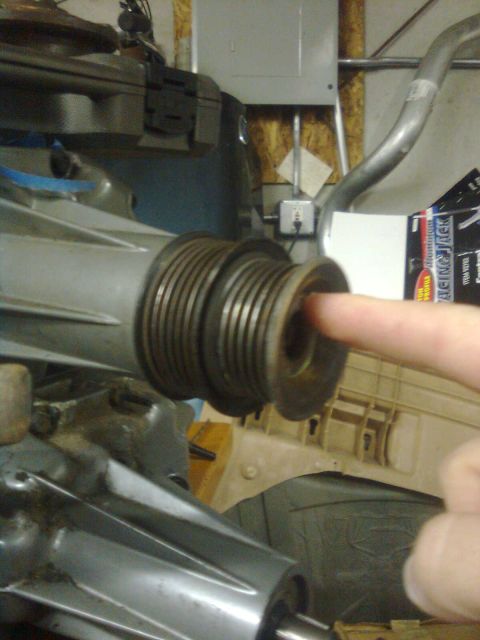 1984 Ford Bronco - Close-up of a ribbed pulley system part being pointed at by a finger.