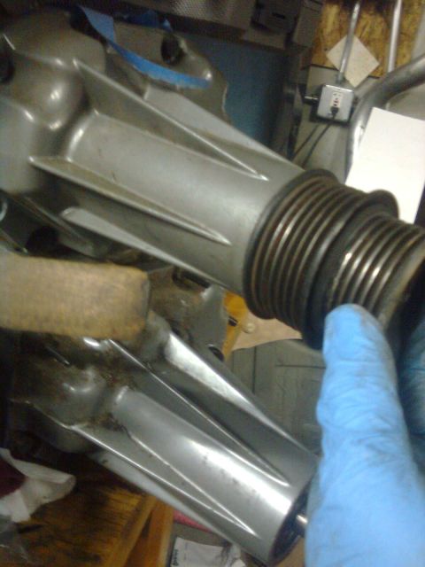 1984 Ford Bronco - Close-up of a metal splined shaft or slip yoke with a black accordion-style rubber boot at one end, held by a hand in a blue nitrile glove…