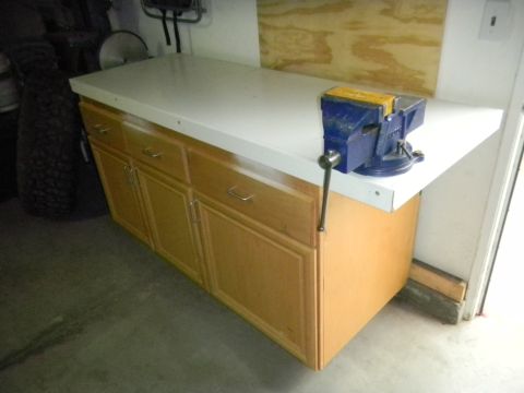 1997 Ford Ranger - A workbench with a blue vise is shown in a garage setting, next to a stack of tires.