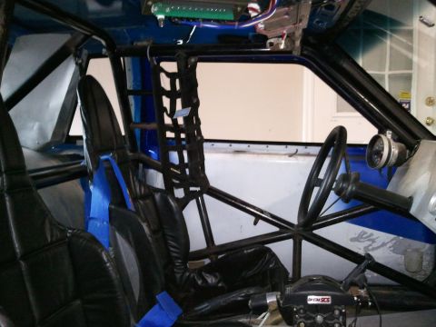 1967 Ford Mustang - The interior of a modified vehicle features a roll cage, racing seats, and a steering wheel, suggesting it's set up for racing.