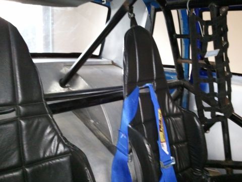 1967 Ford Mustang - Interior view of a vehicle's racing seats and roll cage, with blue safety harnesses visible.