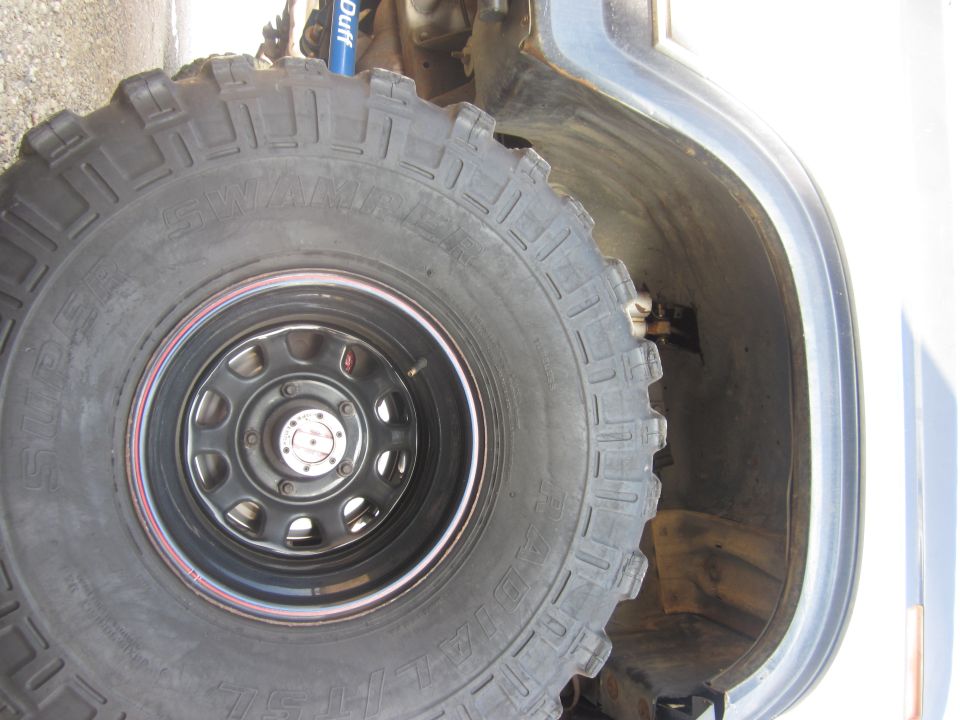 Close-up of a large off-road tire and wheel well with a blue shock absorber visible
