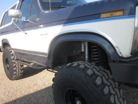 1985 Ford Bronco - Side view of a lifted 1985 Ford Bronco with custom side steps and off-road tires.