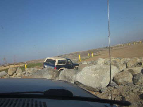 1985 Ford Bronco - A Ford Bronco is shown driving over large rocks on a clear day.