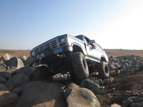 1985 Ford Bronco - Ford Bronco tackling a challenging off-road course with large boulders.