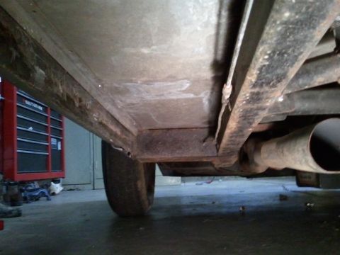 1967 Ford Mustang - Underside view of a vehicle, showing frame components, exhaust, and a tire. A red toolbox is in the background.