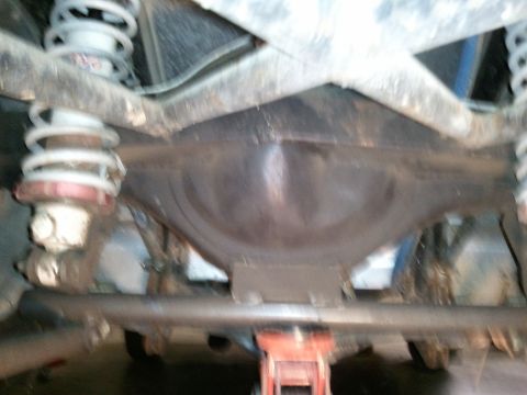 1967 Ford Mustang - Underside view of a vehicle's rear axle and suspension system, supported by a jack.