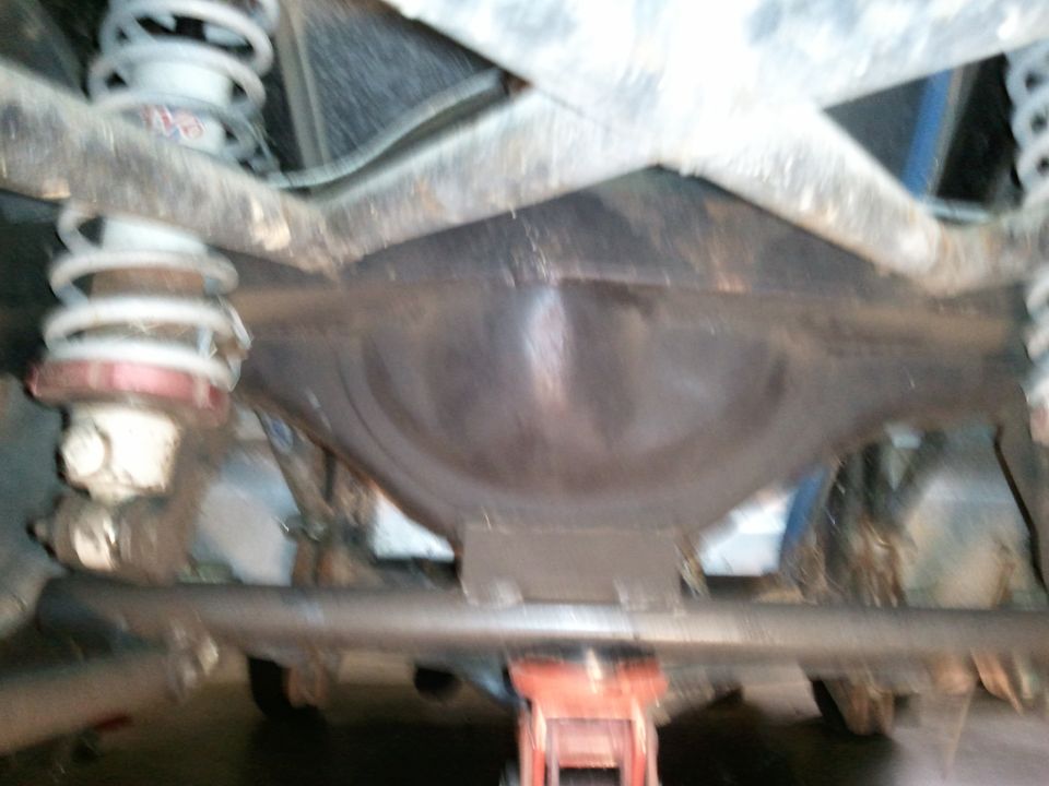 Rear view of solid axle differential housing with white coil-over springs and tube crossmember