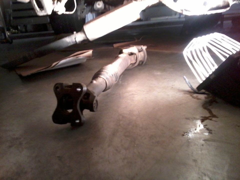 Driveshaft removed from vehicle, lying on concrete floor