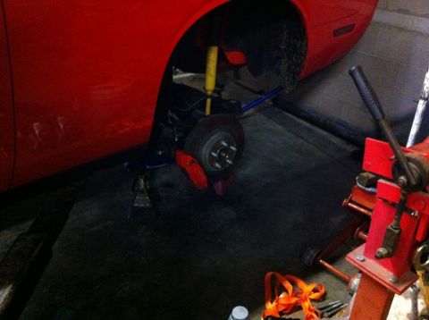 2010 Dodge Challenger - A red Dodge Challenger is shown with its front wheel removed, undergoing maintenance or repair.