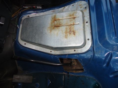 1987 Ford F-150 - Interior view of a blue truck cab showing a rusted metal panel and exposed floor area.