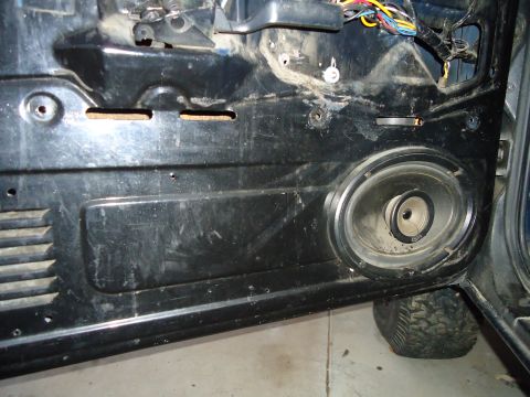 1987 Ford F-150 - The interior of a vehicle door panel shows a speaker and wiring, with a tire visible underneath.