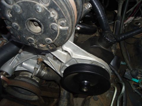 1987 Ford F-150 - Close-up view of an engine's water pump and pulley system, showing various hoses and electrical connections.