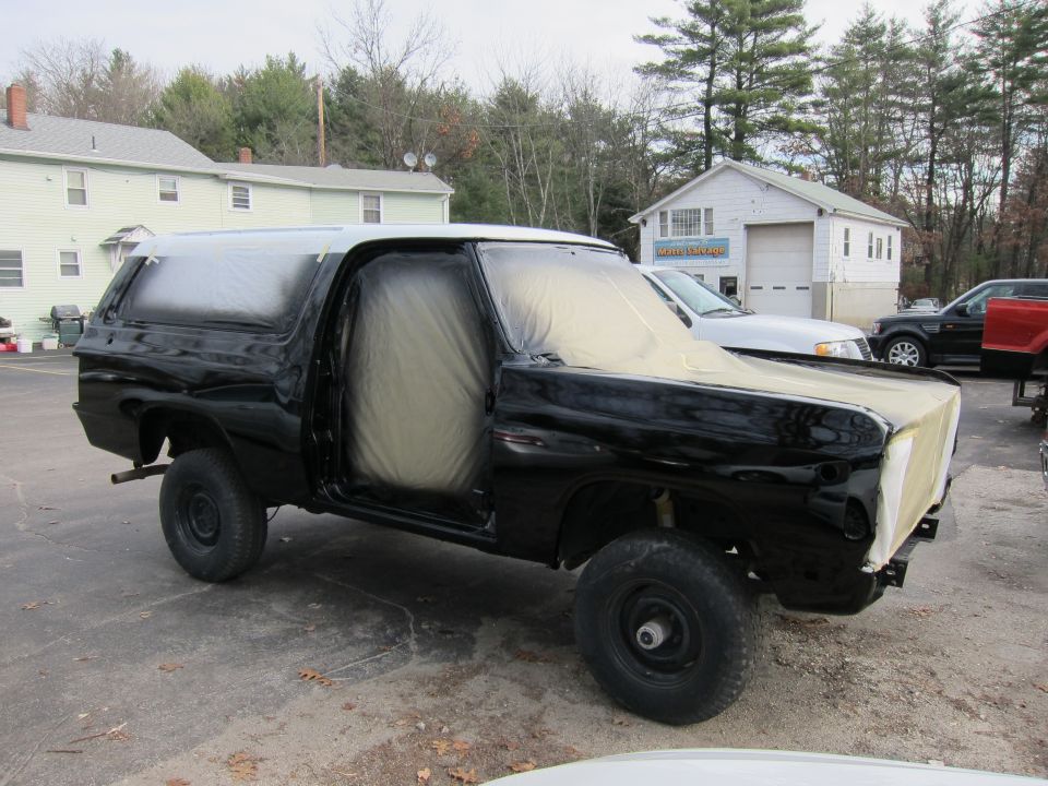Black K5 Blazer with doors and hood covered in plastic, parked outside a garage