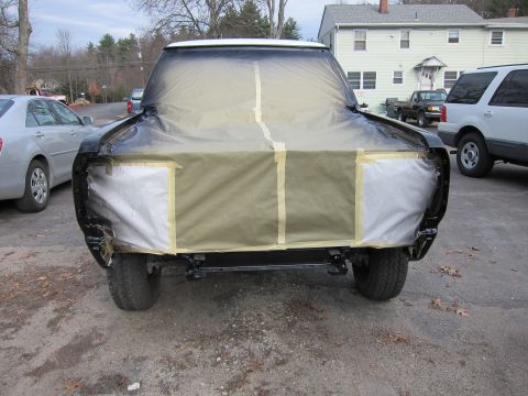 1987 Dodge 1500 - A truck's front end is covered in protective materials, indicating preparation for a paint job.